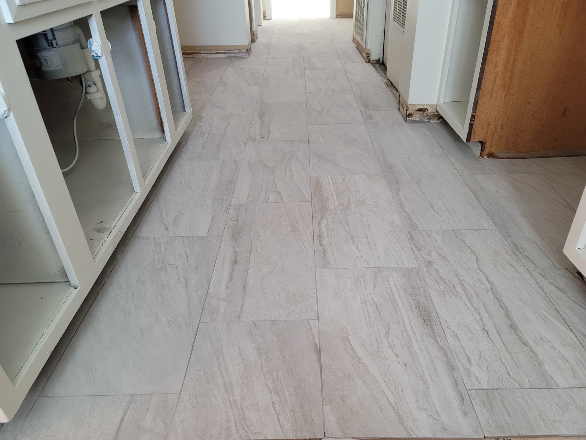 Newly laid large-format tile floor running down a hallway